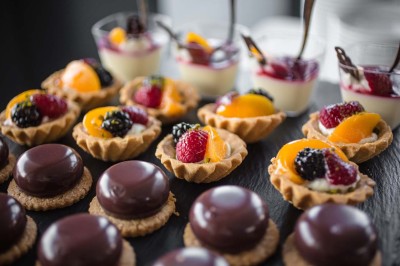 Salle de réception éclairée en bleu avec des tables rondes dressées et des écrans disposés autour.