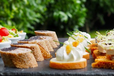 Salle de réception éclairée en bleu avec des tables rondes dressées et des écrans disposés autour.