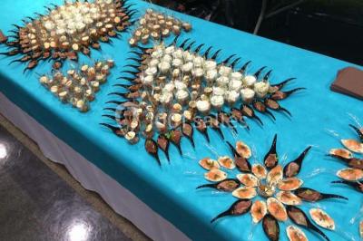 Table décorée pour un dîner, avec nappes blanches, serviettes pliées, lanternes, fleurs et couverts disposés.