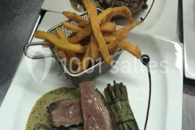 Table décorée pour un dîner, avec nappes blanches, serviettes pliées, lanternes, fleurs et couverts disposés.