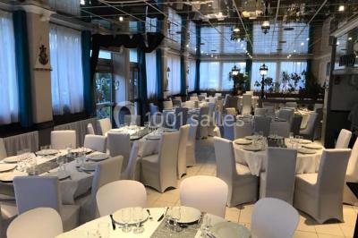 Table décorée pour un dîner, avec nappes blanches, serviettes pliées, lanternes, fleurs et couverts disposés.