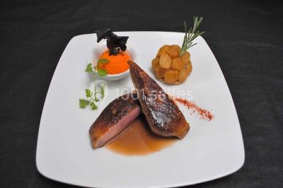 Dessert raffiné composé d'une mousse rose, d'une sauce rouge en verrine et d'un carré de chocolat décoratif.