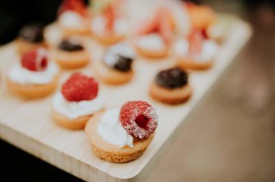 Dessert raffiné composé d'une mousse rose, d'une sauce rouge en verrine et d'un carré de chocolat décoratif.