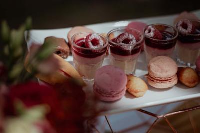 Dessert raffiné composé d'une mousse rose, d'une sauce rouge en verrine et d'un carré de chocolat décoratif.