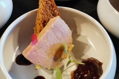 Dessert raffiné composé d'une mousse rose, d'une sauce rouge en verrine et d'un carré de chocolat décoratif.