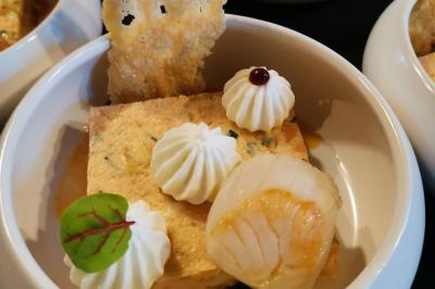 Dessert raffiné composé d'une mousse rose, d'une sauce rouge en verrine et d'un carré de chocolat décoratif.