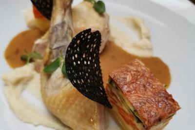 Dessert raffiné composé d'une mousse rose, d'une sauce rouge en verrine et d'un carré de chocolat décoratif.