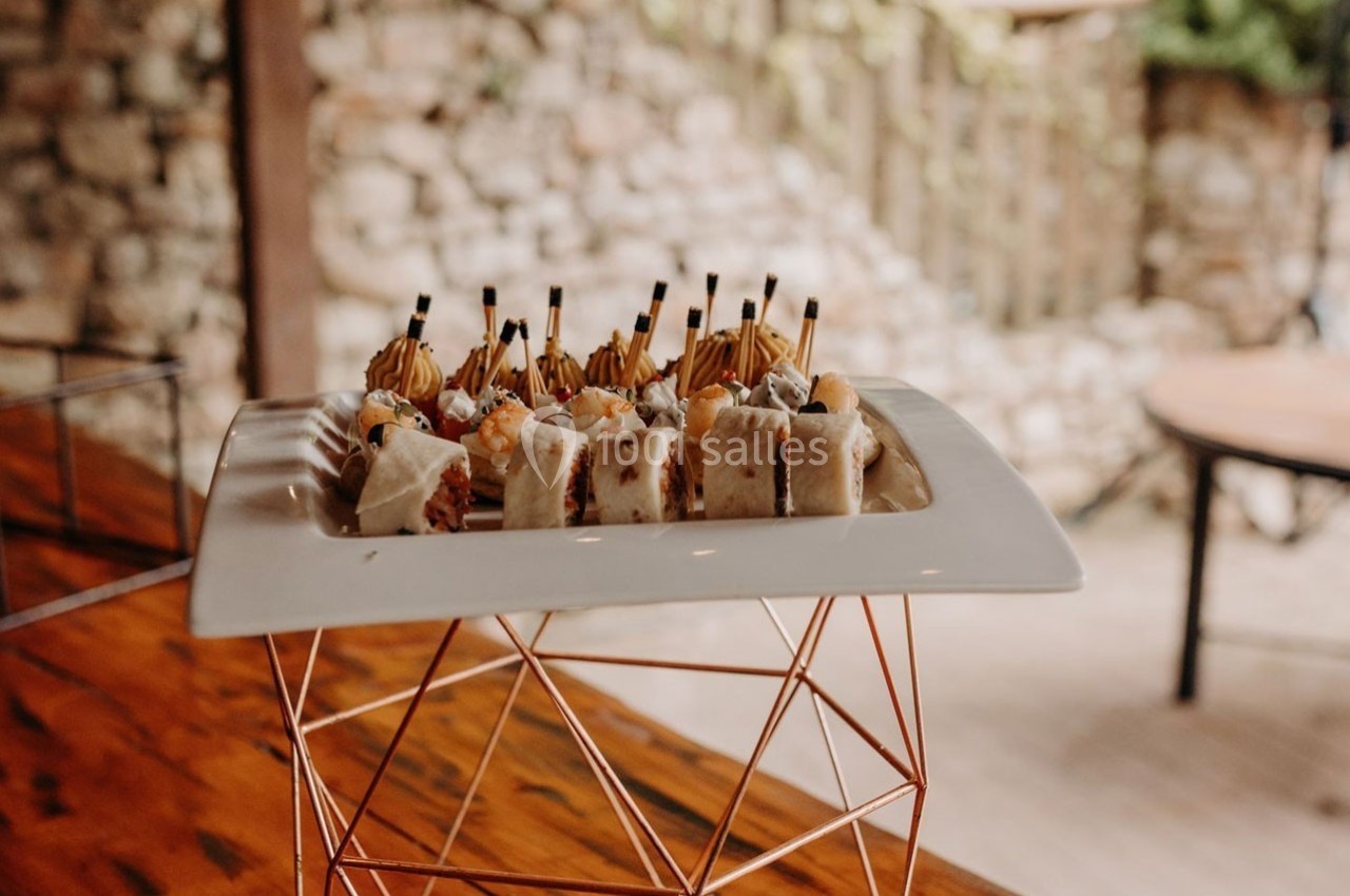 Assiette de sushis variés présentée sur un support géométrique en métal, posée sur une table en bois.