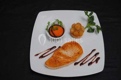 Dessert raffiné composé d'une mousse rose, d'une sauce rouge en verrine et d'un carré de chocolat décoratif.