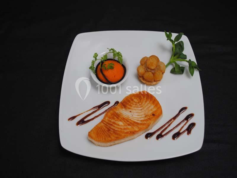 Assiette gastronomique avec filet de poisson grillé, purée orange, garniture verte et décorations de sauce balsamique.