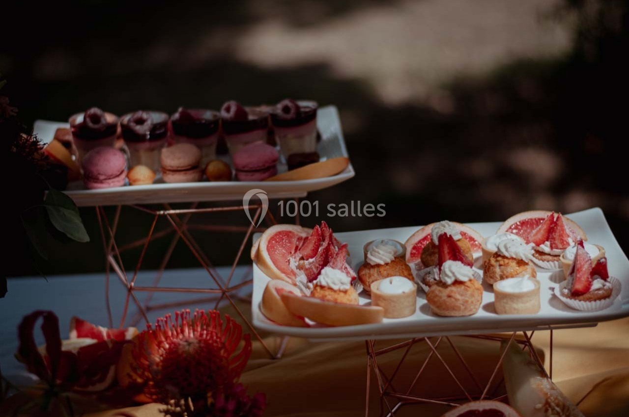 Plateaux de desserts variés comprenant macarons, verrines, choux à la crème et fruits frais, disposés sur une table.