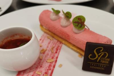 Dessert raffiné composé d'une mousse rose, d'une sauce rouge en verrine et d'un carré de chocolat décoratif.