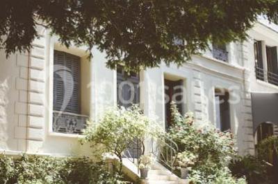 Salle de réception éclairée de lumières violettes, avec un bar, des tables hautes et des rideaux rouges.