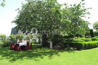 Salle de réception éclairée de lumières violettes, avec un bar, des tables hautes et des rideaux rouges.