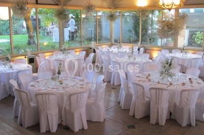 Salle de réception éclairée de lumières violettes, avec un bar, des tables hautes et des rideaux rouges.
