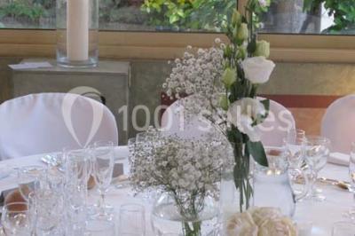 Salle de réception éclairée de lumières violettes, avec un bar, des tables hautes et des rideaux rouges.