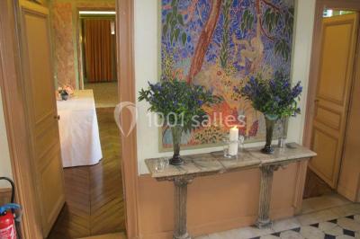 Salle de réception éclairée de lumières violettes, avec un bar, des tables hautes et des rideaux rouges.