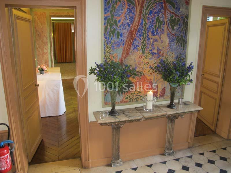 Deux vases de fleurs violettes sur une console en marbre, avec une bougie allumée, dans un intérieur décoré.