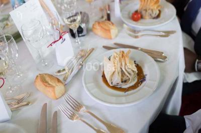 Salle de réception éclairée de lumières violettes, avec un bar, des tables hautes et des rideaux rouges.