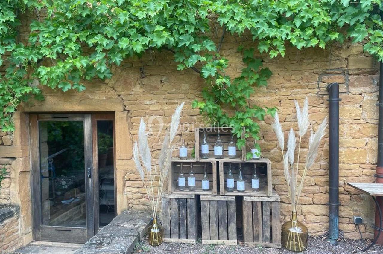 Mur en pierre recouvert de vigne, avec des caisses en bois contenant des bougies et des vases décorés de pampas.