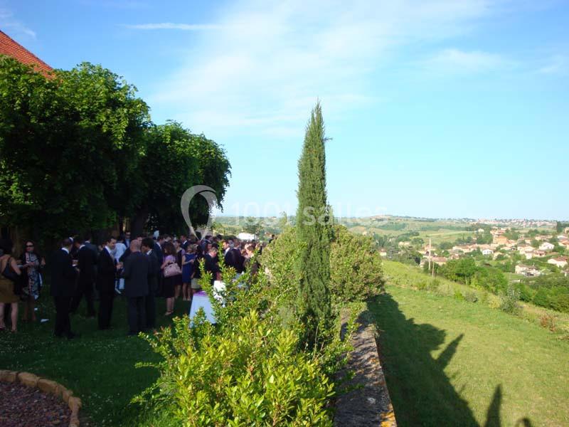 Groupe de personnes rassemblées dans un jardin verdoyant avec vue sur une campagne ensoleillée.