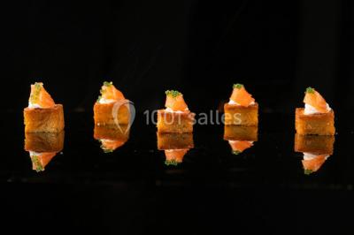 Tables décorées pour un événement en plein air, disposées devant une maison aux volets bleus et murs couverts de lierre.