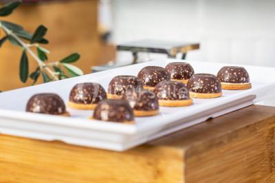 Tables décorées pour un événement en plein air, disposées devant une maison aux volets bleus et murs couverts de lierre.