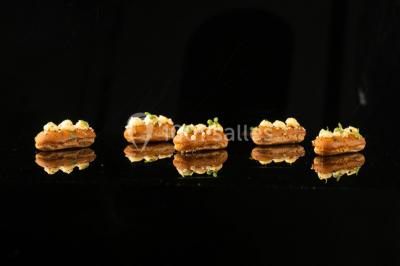 Tables décorées pour un événement en plein air, disposées devant une maison aux volets bleus et murs couverts de lierre.