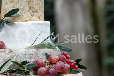 Tables décorées pour un événement en plein air, disposées devant une maison aux volets bleus et murs couverts de lierre.