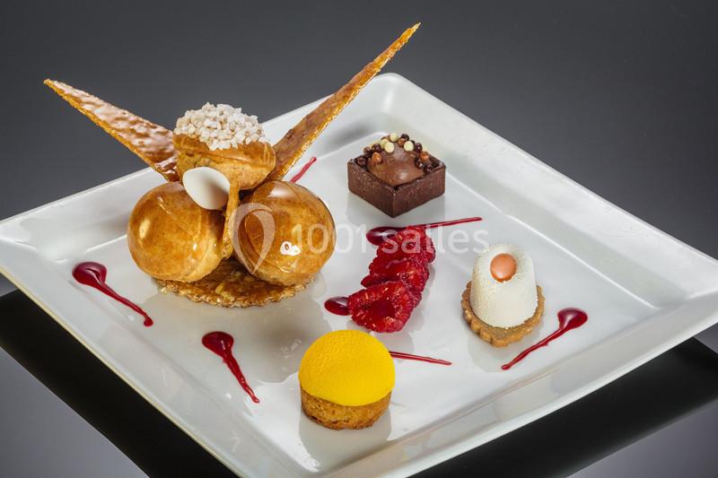 Assortiment de desserts raffinés présentés sur une assiette blanche, avec des textures et couleurs variées.