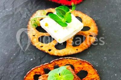 Gros plan sur un macaron rouge garni de crème blanche, posé sur une surface sombre.