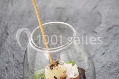 Gros plan sur un macaron rouge garni de crème blanche, posé sur une surface sombre.