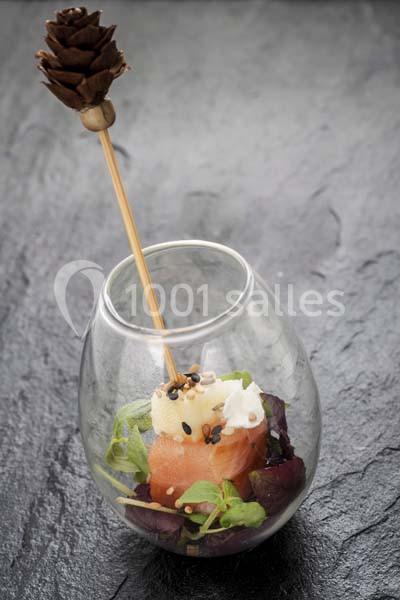 Bouchée de saumon et fromage frais sur lit de salade, présentée dans un verre avec une brochette décorative.