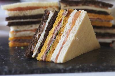 Gros plan sur un macaron rouge garni de crème blanche, posé sur une surface sombre.