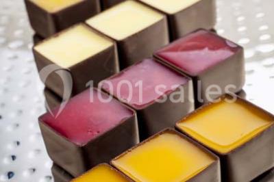 Gros plan sur un macaron rouge garni de crème blanche, posé sur une surface sombre.