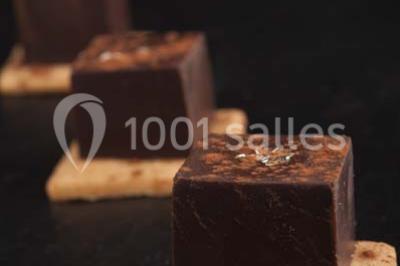 Gros plan sur un macaron rouge garni de crème blanche, posé sur une surface sombre.