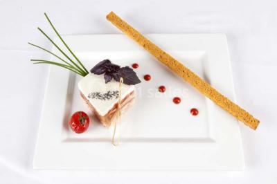 Gros plan sur un macaron rouge garni de crème blanche, posé sur une surface sombre.