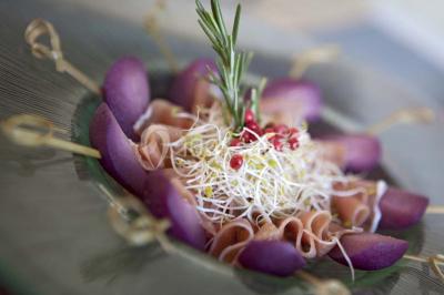 Gros plan sur un macaron rouge garni de crème blanche, posé sur une surface sombre.