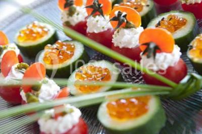 Gros plan sur un macaron rouge garni de crème blanche, posé sur une surface sombre.