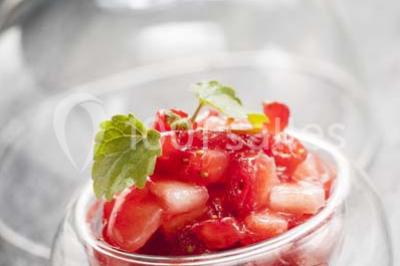 Gros plan sur un macaron rouge garni de crème blanche, posé sur une surface sombre.
