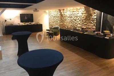 Gros plan sur un macaron rouge garni de crème blanche, posé sur une surface sombre.