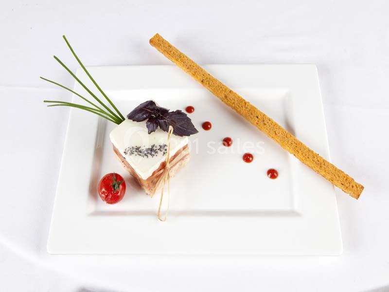 Assiette gastronomique avec un mille-feuille salé, tomate cerise, herbes fraîches, points de sauce et biscuit long.