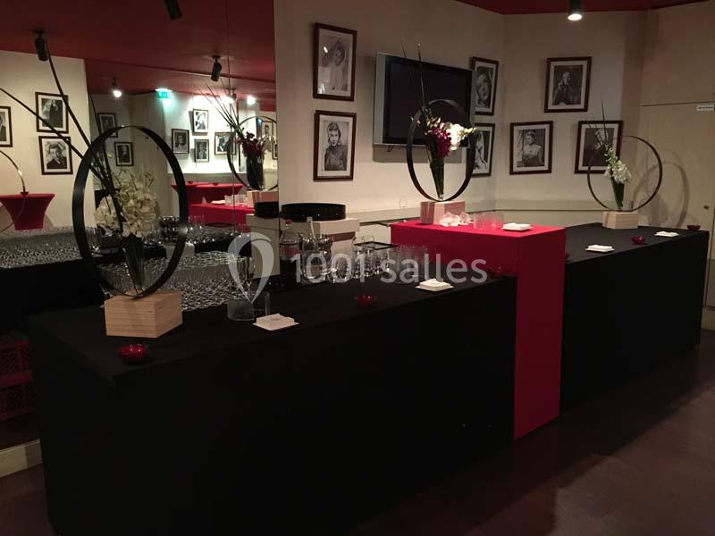 Comptoir décoré avec des fleurs et des verres, dans une salle ornée de photos en noir et blanc sur les murs.