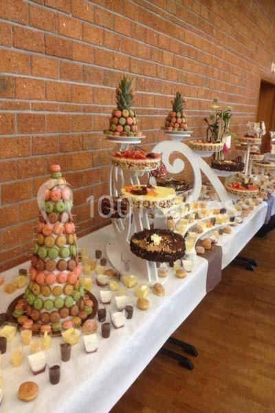 Buffet de desserts variés avec pyramides de macarons, gâteaux et verrines sur une table décorée.