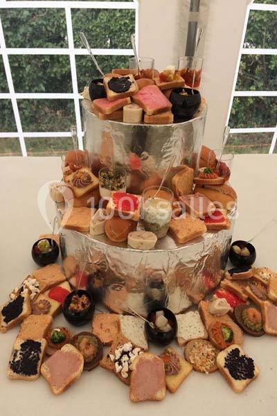 Plateau de toasts variés et amuse-bouches disposés en étages sur une structure argentée, dans un cadre de réception.