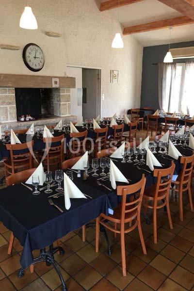 Salle de restaurant avec tables dressées, nappes noires, serviettes blanches pliées et chaises en bois.