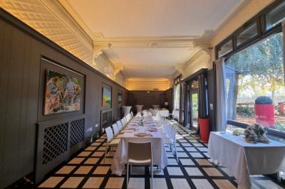 Un chef cuisine sur un brasero dans un jardin, entouré de tables et de végétation.