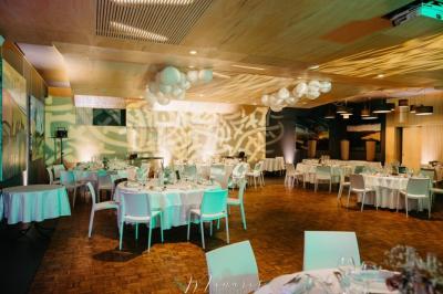 Un chef cuisine sur un brasero dans un jardin, entouré de tables et de végétation.