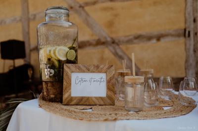 Un chef cuisine sur un brasero dans un jardin, entouré de tables et de végétation.