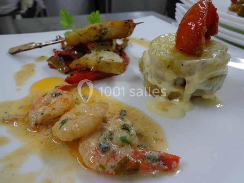 Assiette gastronomique avec crevettes en sauce, légumes grillés sur brochette et gratin de pommes de terre.